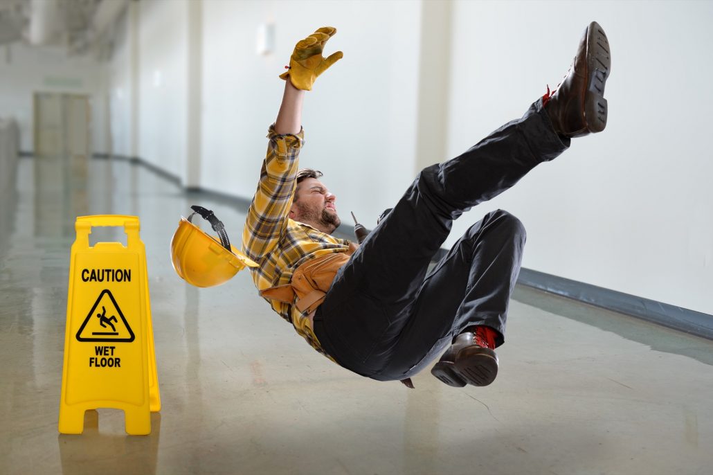 Person Falling On The Floor Next To A Wet Floor Sign