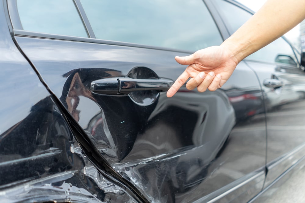 Person Pointing To A Damaged Car