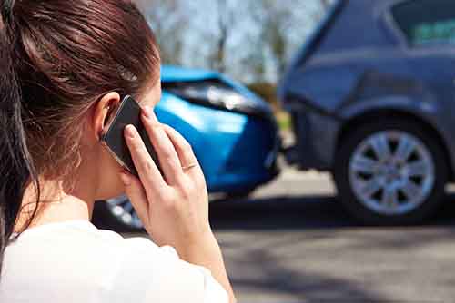 A photo of a Coral Springs personal injury attorney standing next to a damaged car involved in a car accident.