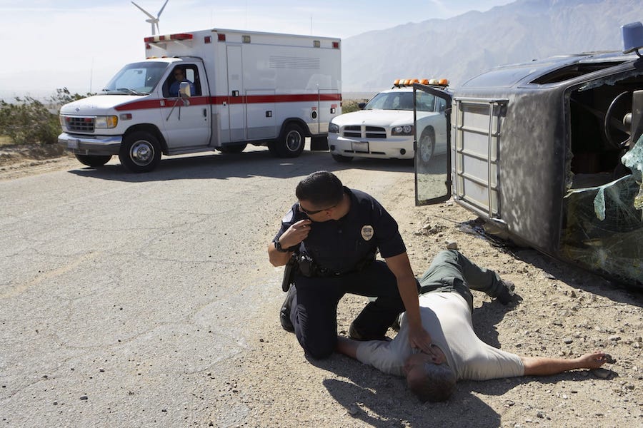 Police Officer Checking The Pulse Of A Body On The Ground