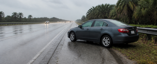 Hydroplaning accident claim scene with a car stopped on a rain-soaked Florida highway