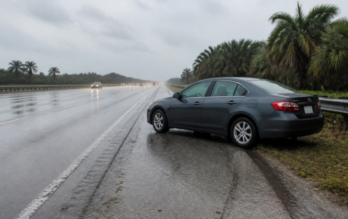 Hydroplaning accident claim scene with a car stopped on a rain-soaked Florida highway