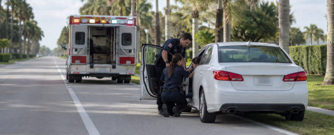 Sudden medical emergency crash claim scene with paramedics assisting a driver beside an unbranded car